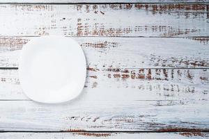 een leeg ronde wit bord Aan een blauw houten tafel. foto