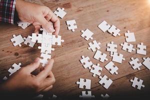 handen met puzzelstuk op houten tafel achtergrond, succes business, oplossingsstrategie, teamwork partnerschap concept foto