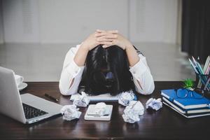 spanning bedrijf vrouw persoon van moeilijk werk, depressie in kantoor. moe en angstig werknemer vrouw met ongelukkig Bij probleem functie. jong zakenvrouw zittend verdrietig voorkant van laptop computer Aan bureau. foto