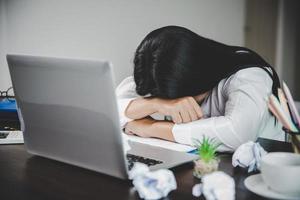 spanning bedrijf vrouw persoon van moeilijk werk, depressie in kantoor. moe en angstig werknemer vrouw met ongelukkig Bij probleem functie. jong zakenvrouw zittend verdrietig voorkant van laptop computer Aan bureau. foto