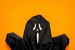 zwart spookachtig geest vel met oranje achtergrond voor halloween minimaal achtergrond concept. foto