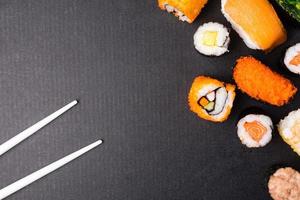 top visie van sushi reeks en eetstokjes Aan zwart achtergrond, Japans voedsel. vrij ruimte voor tekst foto