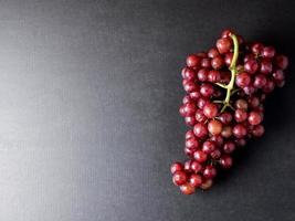 top visie van rood druiven Aan een zwart achtergrond. vrij ruimte voor tekst foto