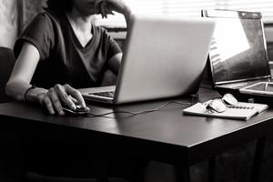 gewoontjes jong vrouw gebruik makend van een laptop Aan de bureau. zwart en wit toon