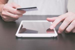 dichtbij omhoog van mannetje handen gebruik makend van tablet en Holding credit kaart Aan de tafel, online boodschappen doen concept. foto