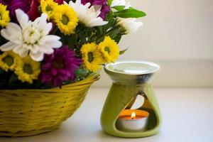 olie brander met chrysanten door de kant. aromatherapie brander. olie, aromatherapie brander, bloemen en kaarsen voor spa en ontspanning. foto