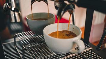 detailopname van espresso gieten van koffie machine vloeiende in de koffie kop maken koffie voor klanten in de cafe. foto