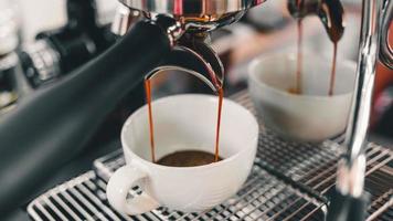detailopname van espresso gieten van koffie machine vloeiende in de koffie kop maken koffie voor klanten in de cafe. foto