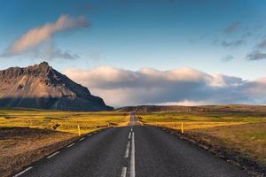 toneel- leeg asfalt Rechtdoor weg met zonlicht en berg visie Bij IJsland foto