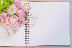 Open Notitie boek met roze roos bloemen Aan houten achtergrond foto