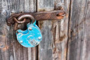 blauw oud roestig ontgrendeld hangslot Aan houten deur foto