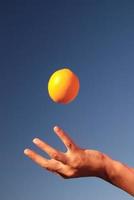 vrouw hand- balanceren oranje in lucht foto
