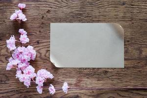 bruin papier en roze bloemen Aan houten achtergrond foto