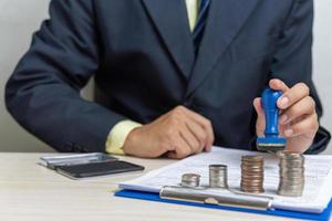 zakenman Holding een rubber postzegel pompen documenten van financieel goedkeuring of bank lening Aan desk.business investering concept. foto