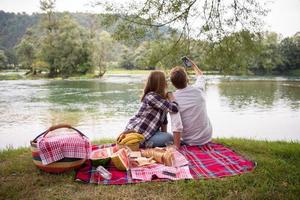 paar nemen een selfie door mobiel telefoon terwijl genieten van picknick tijd foto