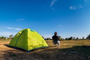 Aziatische vrouwelijke toeristen zitten gelukkig vrij met groene tent voor reiziger zit op breed veld, met uitzicht op de avondtijd van privégebied thailand voor kampeervakantie tijdens lange vakantie om te reizen. foto