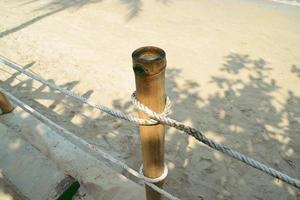 touw gebonden knoop Bij bamboe hout Aan de strand kant. foto