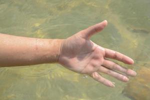 detailopname iemand hand- Speel de water in de zee. foto