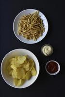 heerlijk aardappel chips met sauzen Aan een zwart achtergrond. voorafje van aardappel chips met saus. snel voedsel Aan een zwart achtergrond. foto