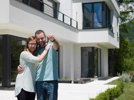 paar knuffelen in voorkant van nieuw luxe huis foto