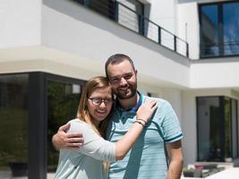 paar knuffelen in voorkant van nieuw luxe huis foto