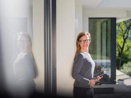 Dames gebruik makend van tablet computer in voorkant van luxe huis villa foto