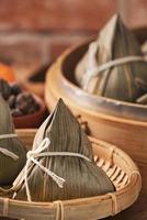 rijst- knoedel - Chinese zongzi voedsel in een stoomboot Aan houten tafel met rood steen muur, venster achtergrond Bij huis voor draak boot festival concept, dichtbij omhoog. foto