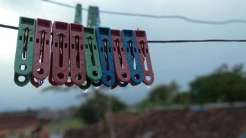 kleren haringen van divers kleuren hangend Aan de Kledinglijn tegen de lucht foto