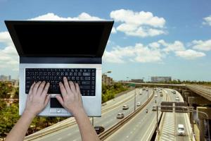 vrouw gebruik makend van laptop met wazig snelweg achtergrond foto
