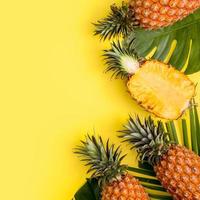 mooie ananas op tropische palm monstera bladeren geïsoleerd op heldere pastel gele achtergrond, bovenaanzicht, plat lag, overhead boven zomerfruit.