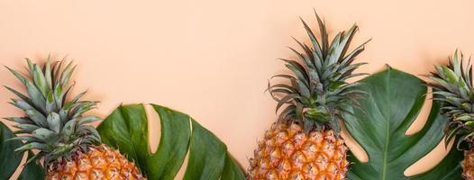 mooi ananas Aan tropisch palm monstera bladeren geïsoleerd Aan helder pastel oranje roze achtergrond, top visie, vlak leggen, overhead bovenstaand zomer fruit. foto