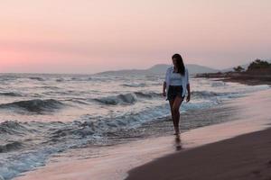 gelukkig zorgeloos vrouw genieten van mooi zonsondergang Aan de strand. selectief focus foto
