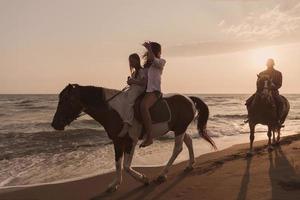 de familie besteedt tijd met hun kinderen terwijl rijden paarden samen Aan een zanderig strand. selectief focus foto