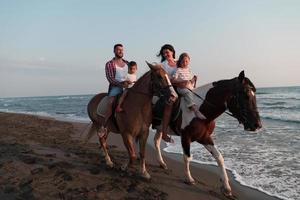 de familie besteedt tijd met hun kinderen terwijl rijden paarden samen Aan een zanderig strand. selectief focus foto