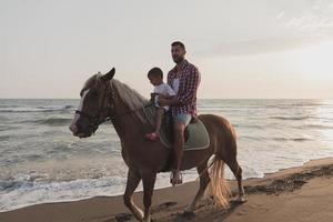 vader en zoon genieten rijden paarden samen door de zee. selectief focus foto