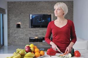 gelukkig mooi blond vrouw bereiden voedsel in de keuken foto