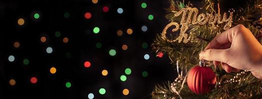 Kerst achtergrond concept-mooie decor snuisterij hangend aan de kerstboom met sprankelende lichte plek, wazige donkere zwarte achtergrond, kopieer ruimte, close-up. foto