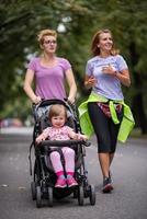 Dames met baby wandelwagen jogging samen foto