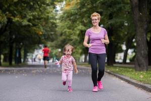 moeder en weinig dochter jogging in stad park foto