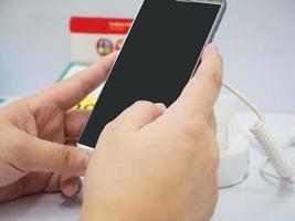 vrouwelijke hand houdt mobiele smartphone vast in mobiele telefoonwinkel foto