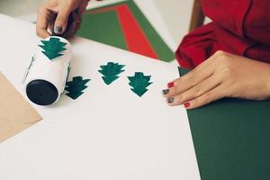 de meisje Bij de tafel maakt Kerstmis geschenken. hand- gemaakt foto