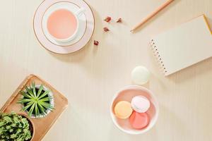 gestileerd voorraad fotografie beige kantoor bureau tafel met blanco notitieboekje, bitterkoekjes, benodigdheden en koffie kop foto