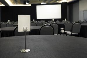 leeg teken en scherm in een conferentie kamer gevulde met tafels en stoelen foto