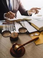 mannelijke advocaat die met contractdocumenten en houten hamer op tafel in rechtszaal werkt. justitie en recht, advocaat, rechter, concept. foto