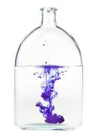paars inkt lost op in water in fles geïsoleerd foto