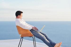 ontspannen jong Mens Bij huis Aan balkon foto