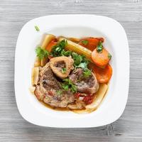 top visie van Italiaans schotel ossobuco Aan grijs bord foto