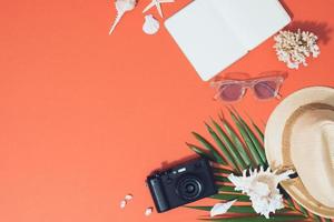 kleurrijk zomer vakantie mode vlak leggen - rietje hoed, camera, zonnebril, zee schelpen Aan helder oranje achtergrond foto