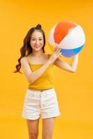 gelukkig jong Aziatisch vrouw Holding strand bal in zomer vakantie reizen Aan oranje achtergrond. foto