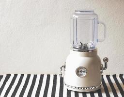 wit wijnoogst blender of smoothie maker Aan zwart en wit streep tafel kleding en wit muur. foto